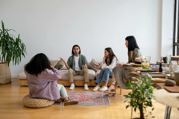 A group of people sitting indoors having a discussion during a relaxed Red Flag Poll meeting.