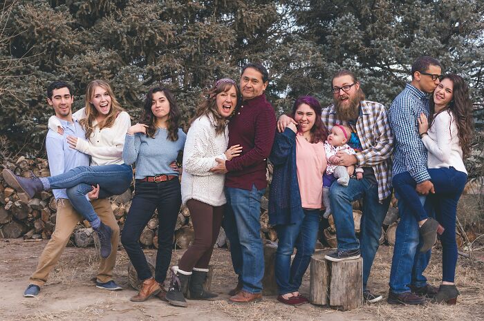 A diverse family group outdoors smiling and posing together for a red flag poll photo in a natural setting.