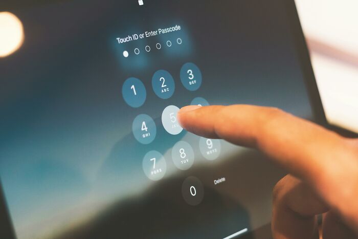 Finger entering passcode on a tablet screen with a red flag poll concept implied by security access.
