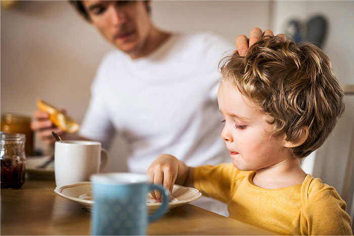 Father and child having breakfast together, illustrating dad&rsquo;s stance on kids&rsquo; diet and custody challenges.