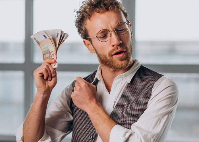 Man holding cash with a confident expression illustrating family conflict over dad&rsquo;s cabin and struggling stepbrother issues.