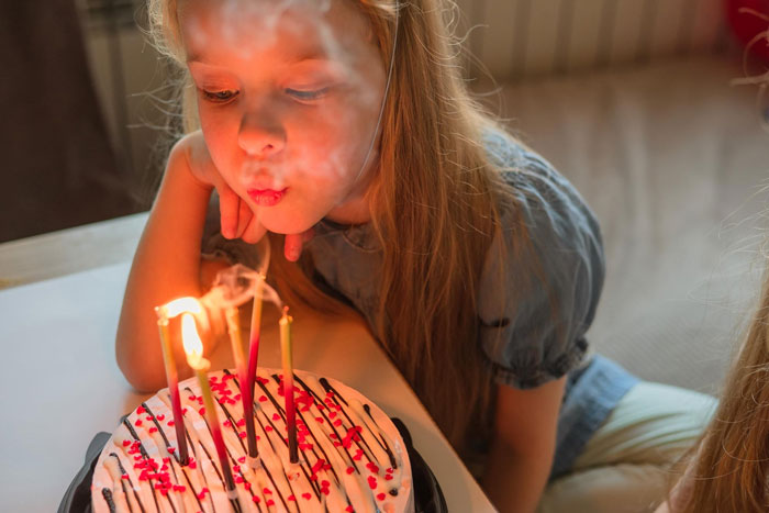 Toddler blowing out birthday cake candles while mom sets boundaries on sharing during sister's birthday celebration. Toddler blowing out birthday cake candles while mom sets boundaries on sharing during sister's birthday celebration.