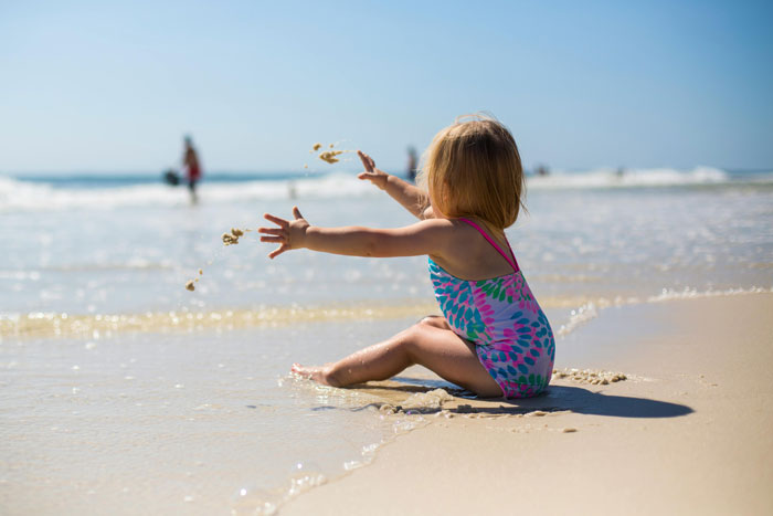Child playing in the sand on a beach, illustrating a beach vacay with kids and family dynamics. Child playing in the sand on a beach, illustrating a beach vacay with kids and family dynamics.