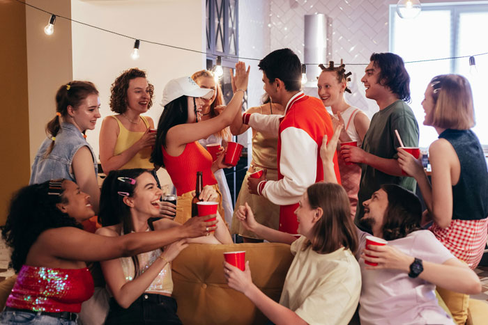Group of students at a lively house party, sharing drinks and enjoying the roommate&rsquo;s celebration together.