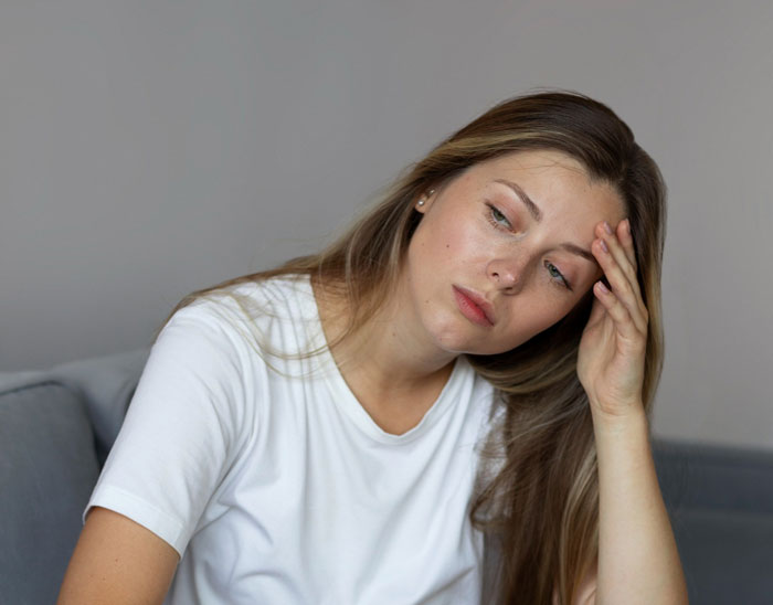 Tired woman in a white shirt looking stressed while babysitting, representing a babysitting nightmare scenario. Tired woman in a white shirt looking stressed while babysitting, representing a babysitting nightmare scenario.