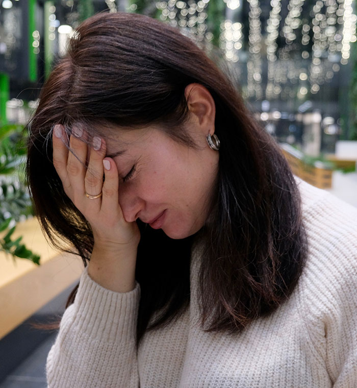 Woman looking stressed with her hand on her face, symbolizing frustration over phone tracking and location privacy issues.