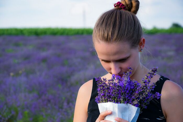Young woman smelling lavender flowers in a field, illustrating the contrast of really good or really bad genes naturally.