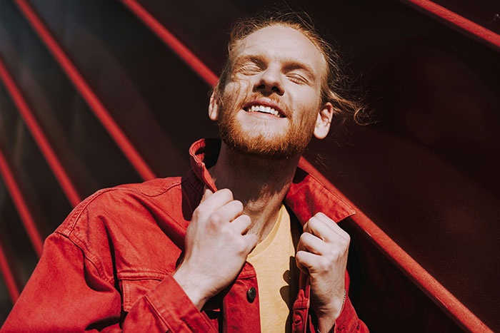 Smiling man in a red jacket standing confidently, embodying tall and loud attitude comebacks to entitled bosses.