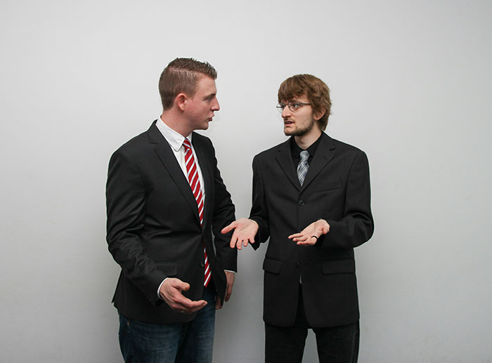 Two men in business suits having a serious discussion, illustrating comebacks to entitled bosses in a professional setting.