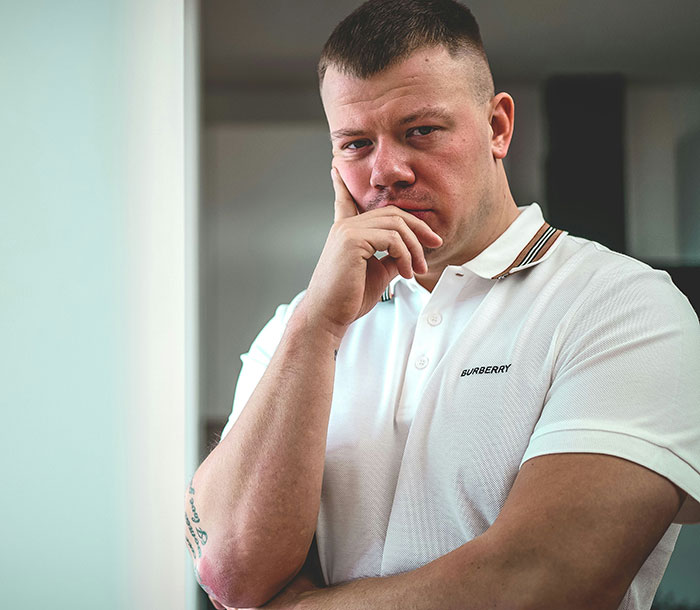 Man in a white polo shirt thoughtfully posing indoors, illustrating confident comebacks to entitled bosses.