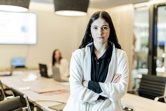 Confident young woman standing with arms crossed in office, showcasing strength and comebacks to entitled bosses.