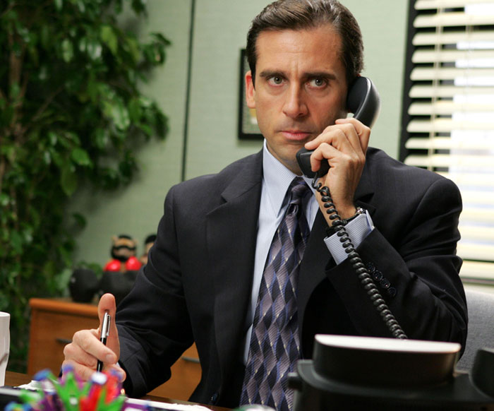 Man in a business suit on the phone at his desk, illustrating comebacks to entitled bosses in a workplace setting.