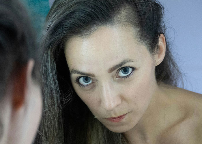 Woman looking intently at herself in the mirror, reflecting on safety tips women picked up the hard way.