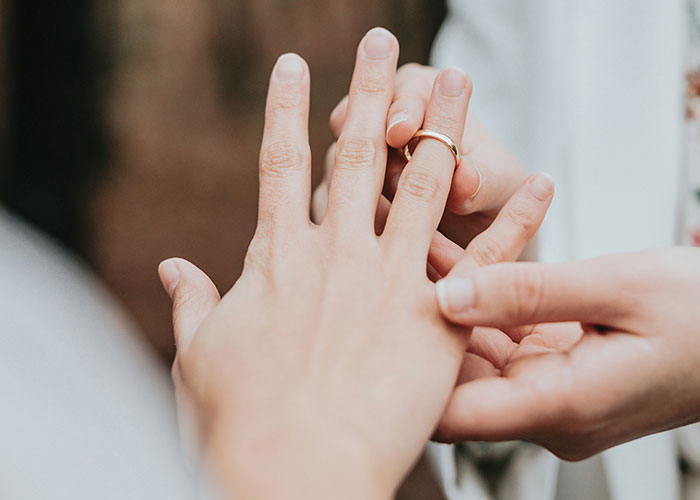 Hands placing a ring on a finger, illustrating symbolic safety tips women apply in personal and relationship settings.