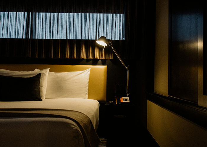 Cozy hotel room at night with bedside lamp on, illustrating safety tips women use for secure lodging environments.