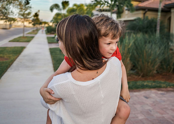Woman carrying child outdoors, illustrating safety tips women picked up the hard way in everyday situations.