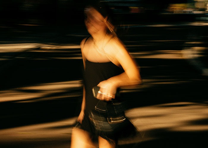 Woman walking at night holding a purse, illustrating safety tips women picked up from experience in urban environment.