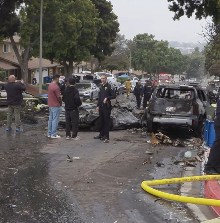 Police and emergency responders investigating aftermath of San Diego plane crash involving famous drummer at controls.