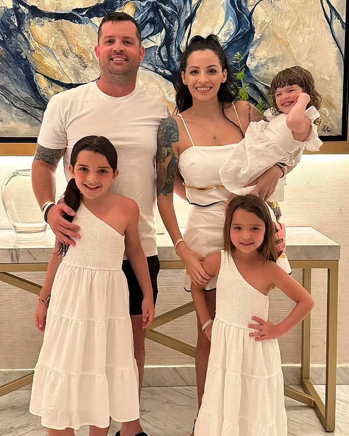 Family portrait showing a man, woman, and three children in white outfits, related to marriage and toddler hot car incident. Family portrait showing a man, woman, and three children in white outfits, related to marriage and toddler hot car incident.