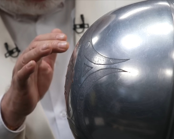 Scientist examining a metallic UFO object with mysterious inscriptions about origin of birth in a lab setting.