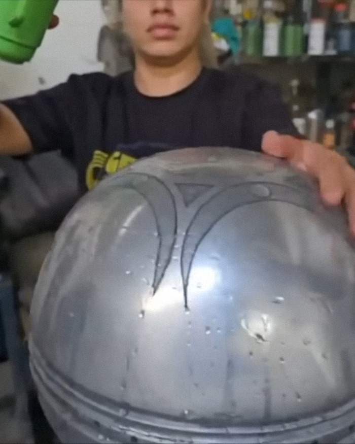 Person holding metallic UFO with ominous symbols about origin of birth in a workshop, scientists breaking silence on discovery.