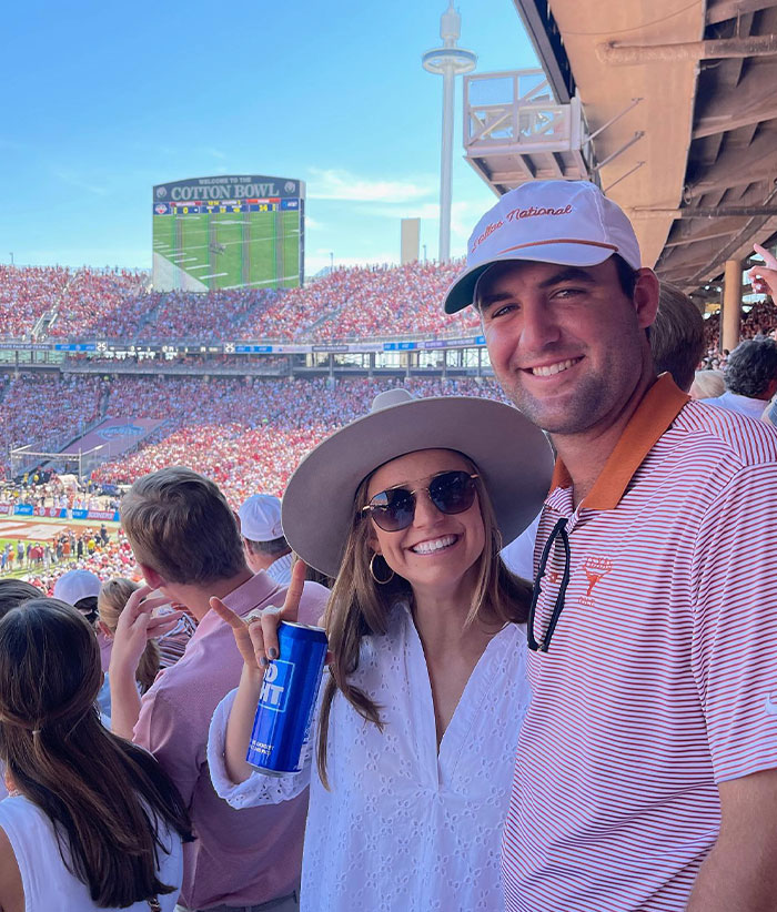 Scottie Scheffler and his wife enjoying a crowded Cotton Bowl stadium, highlighting Scottie Scheffler&rsquo;s net worth and the financial power in golf.