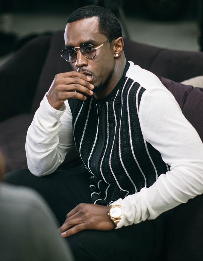Man wearing sunglasses and a black and white sweater sitting thoughtfully, related to Diddy's revolting eating habits revealed by staff. Man wearing sunglasses and a black and white sweater sitting thoughtfully, related to Diddy's revolting eating habits revealed by staff.