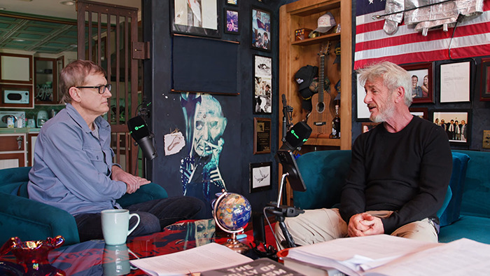 Two men having a conversation in a podcast studio, focusing on Sean Penn&rsquo;s rough appearance and heavy claims about Woody Allen.