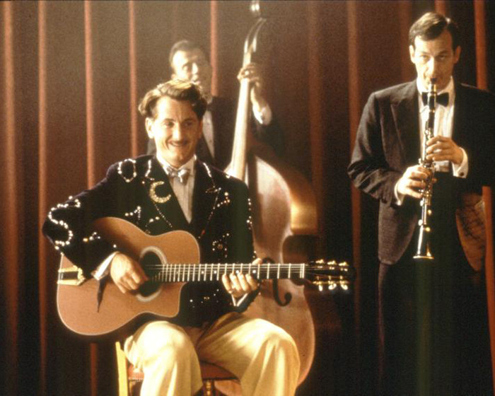 Image of a man playing guitar with two other musicians, relating to Sean Penn's rough appearance and claims about Woody Allen.