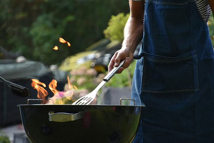 Person wearing apron grilling over open flames, illustrating symptoms that require immediate medical attention.