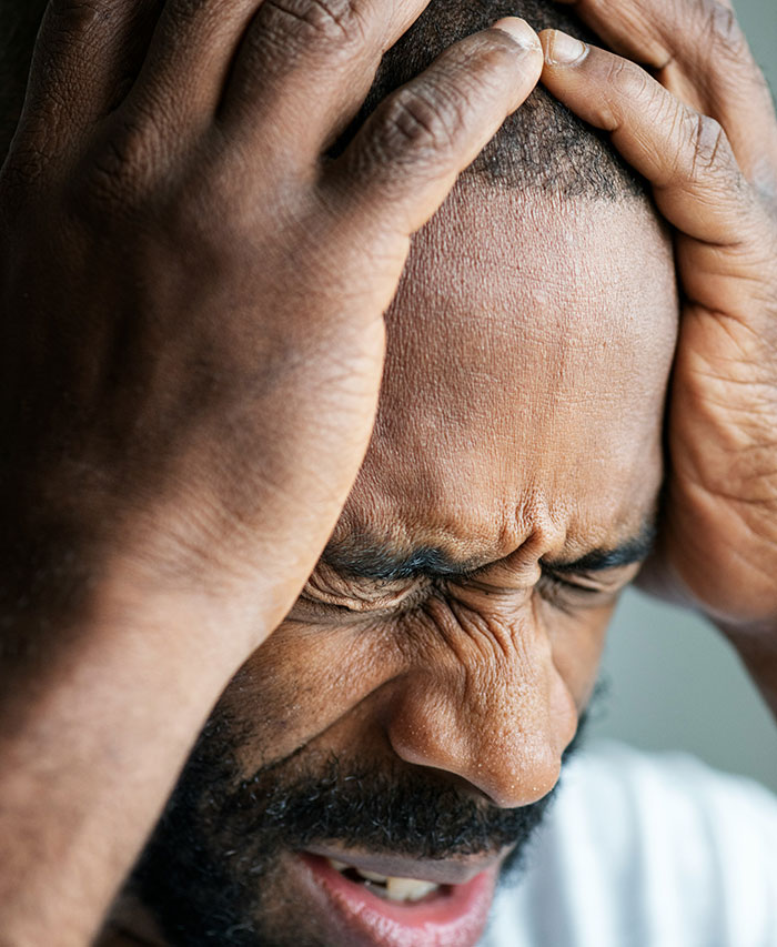 Man holding his head in pain, illustrating symptoms that require immediate medical attention and urgent care.