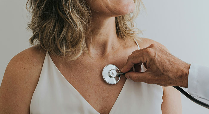 Doctor using stethoscope on patient’s chest, illustrating symptoms that require immediate medical attention.