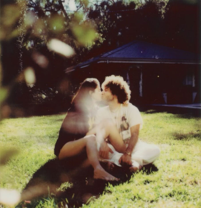 Selena Gomez sitting outdoors on grass with a partner, highlighting her net worth from makeup and music earnings in 2025.