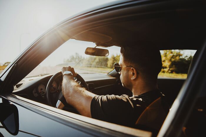 Man wearing sunglasses driving a car in sunlight, representing quick money through unusual ways to earn fast cash.