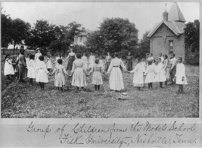 Group of African American children holding hands in a circle outdoors during the 1900 Paris Exposition capturing life moments.