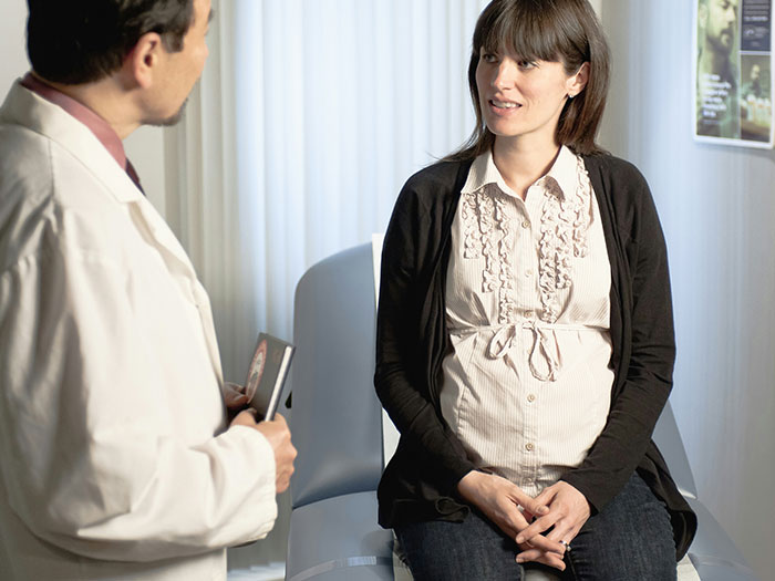 Pregnant woman talking to doctor in a medical office, illustrating times people didn’t know someone could be so stupid.