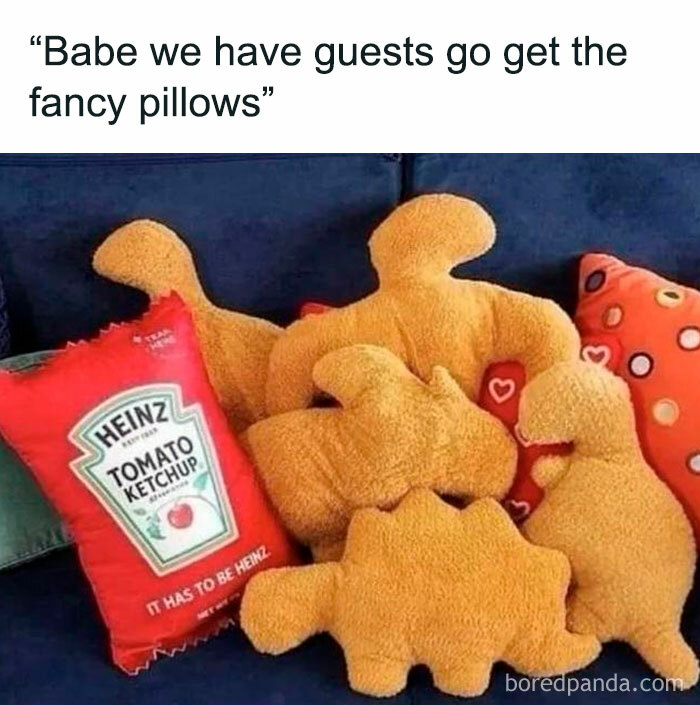 Funny and random plush pillows shaped like dinosaurs and a Heinz ketchup pillow on a couch, humorous shower thoughts theme.