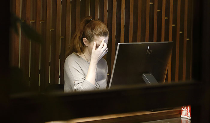 A woman sitting at a desk, covering her face, illustrating the signs she missed while being cheated on.