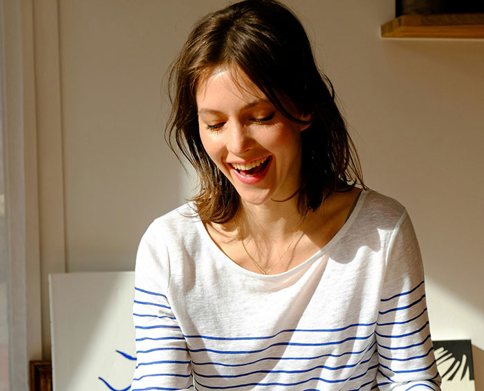 Young woman smiling indoors, representing emotions connected to signs people missed while being cheated on.