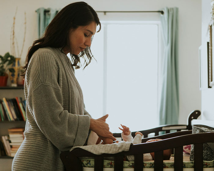 Woman showing irresponsible parenting by neglecting baby in a nursery, highlighting family drama and police threats concerns.