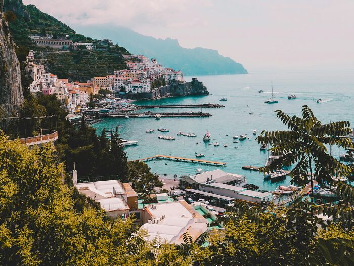 Coastal town with boats docked in a bay surrounded by cliffs, showcasing wonders that prove the world is still full of magic.