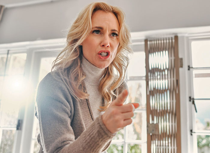 Angry woman pointing finger indoors illustrating tension during girl’s 11th birthday with demanding visiting relatives. Angry woman pointing finger indoors illustrating tension during girl’s 11th birthday with demanding visiting relatives.