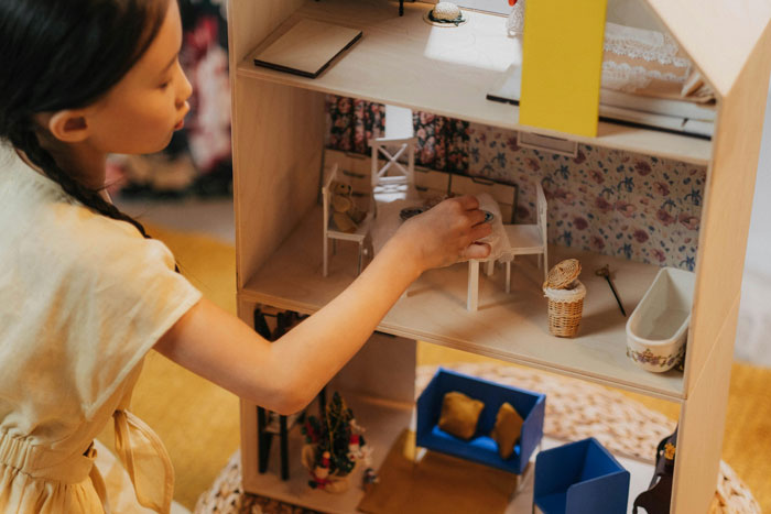 Young girl playing with a dollhouse on her 11th birthday while visiting relatives demand cake, gifts, and attention Young girl playing with a dollhouse on her 11th birthday while visiting relatives demand cake, gifts, and attention