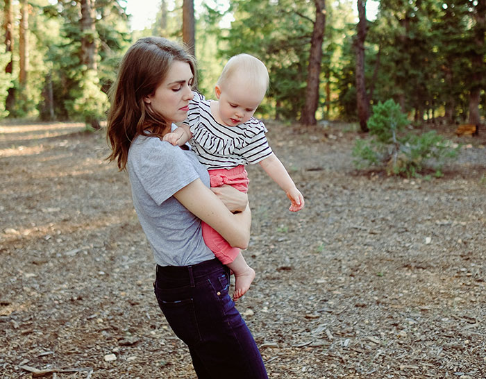Young woman holding a baby outdoors, capturing a moment related to babysitter and baby falling asleep.