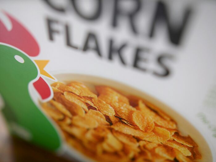 Close-up of a corn flakes cereal box highlighting food prices comparison between the 1980s and now.