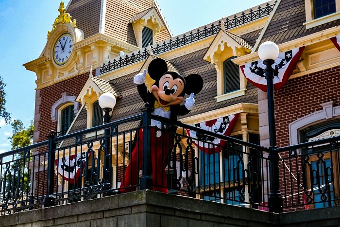 Mickey Mouse character posing on a balcony outside a decorated building, related to fascinating today I learned facts.