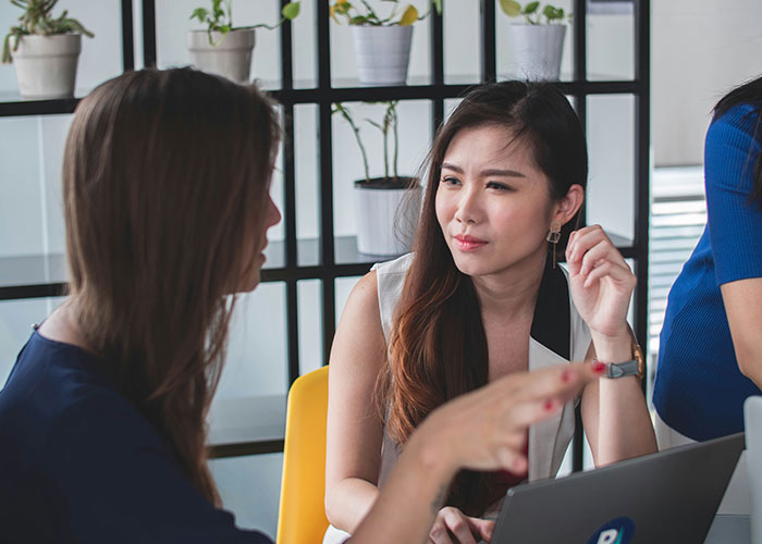 Two women having a serious discussion in an office setting, illustrating things women stopped pretending they like after 30.