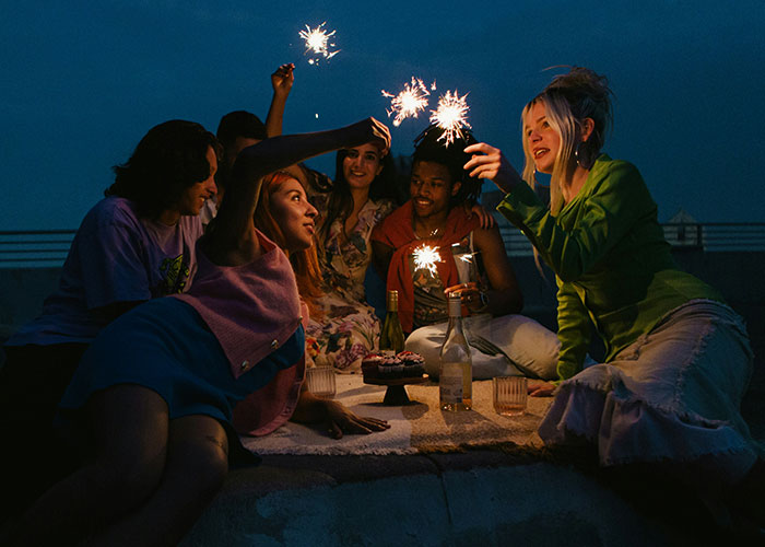 Group of women enjoying an evening outdoors, holding sparklers and celebrating with drinks after 30.