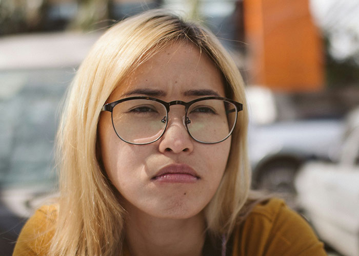 Close-up of a woman wearing glasses with a serious expression, reflecting women stopped pretending they like after 30.