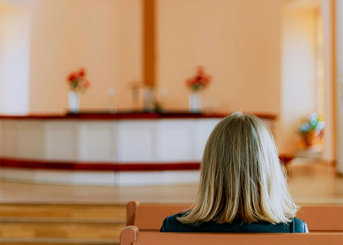 Woman with blonde hair sitting on a bench indoors, reflecting on things women stopped pretending they like after 30.